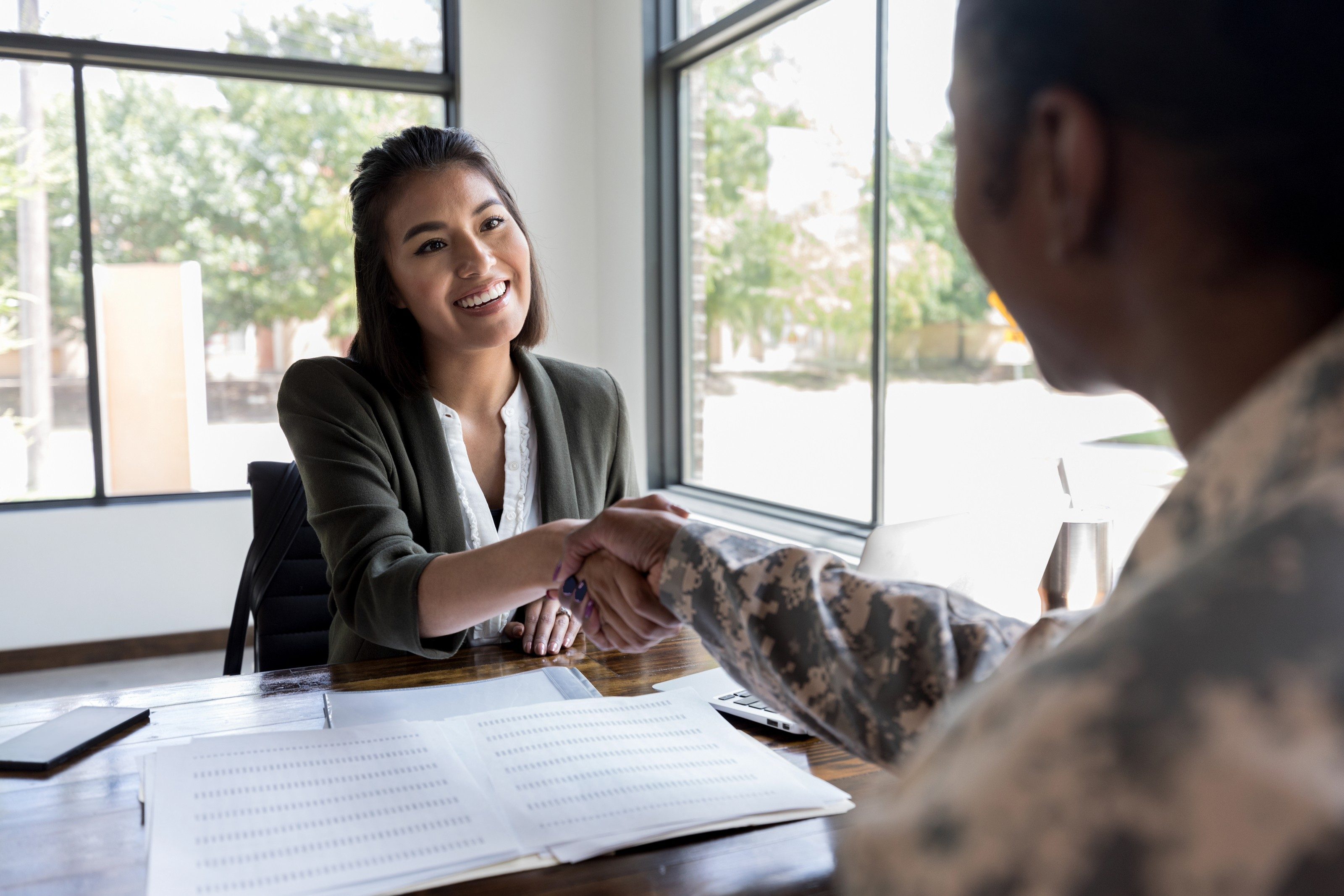 Smiling young female financial advisor greets female soldier.