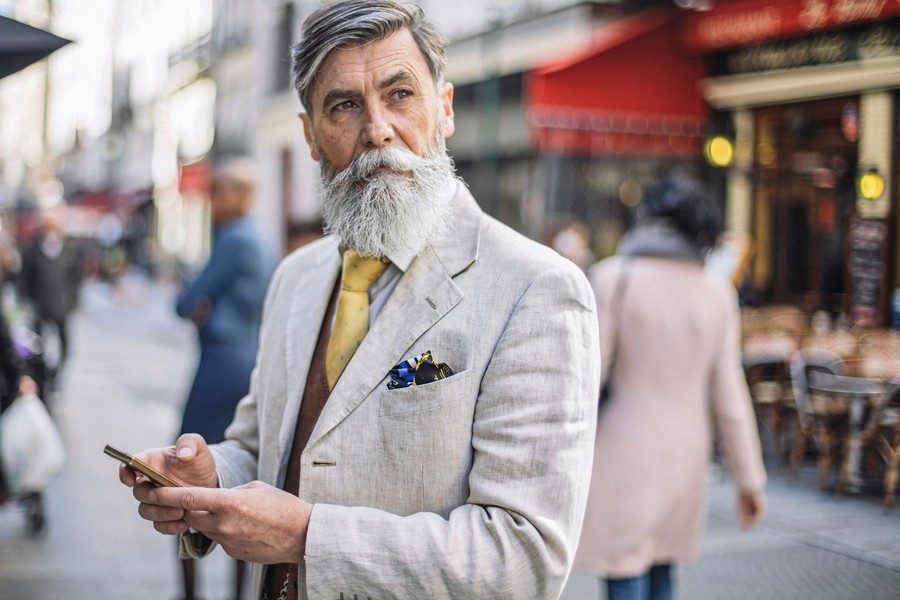 Bearded mature man texting at the streets of Paris.