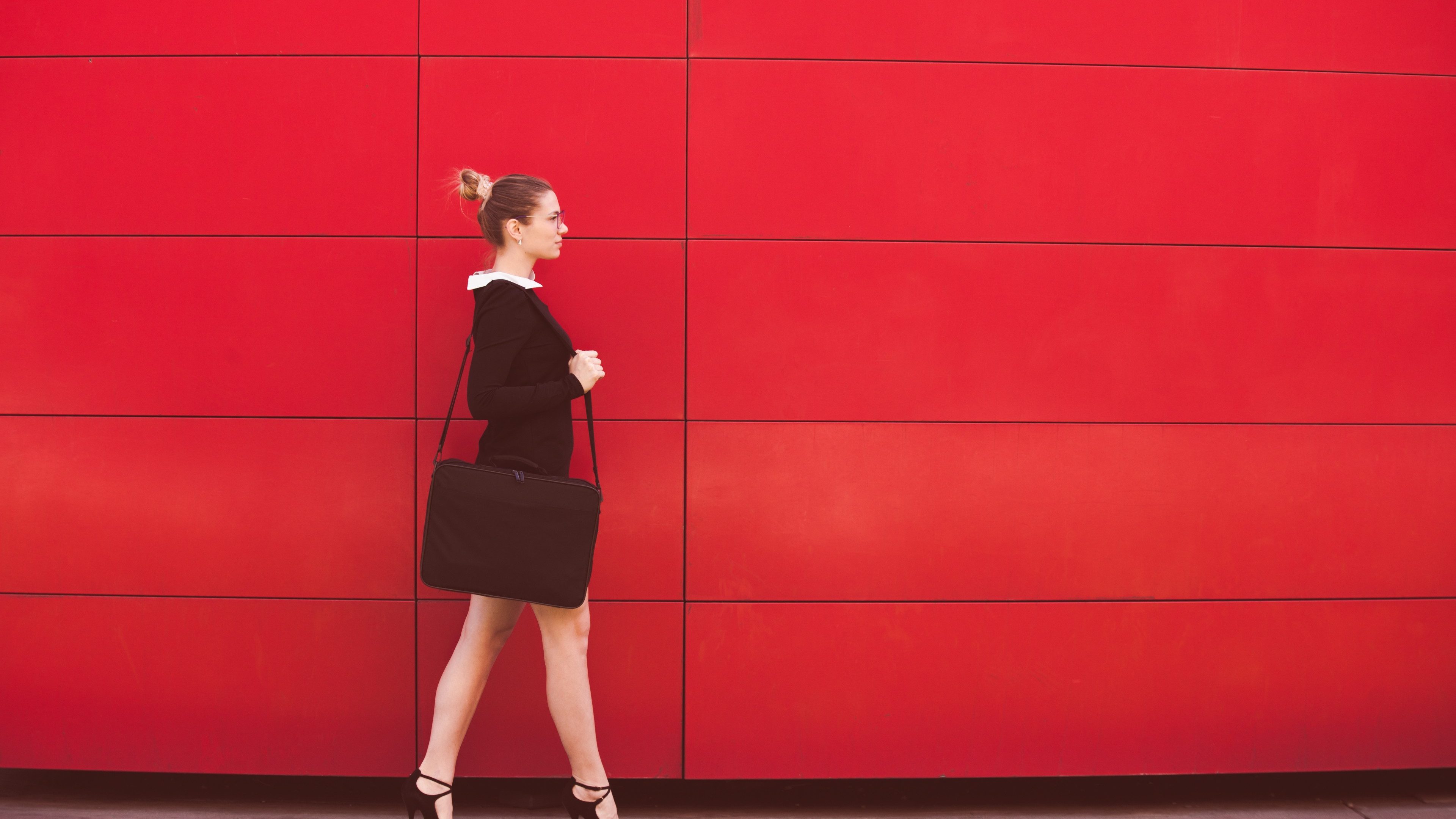 young elegant business woman walk  in front red wall in the city full body shot