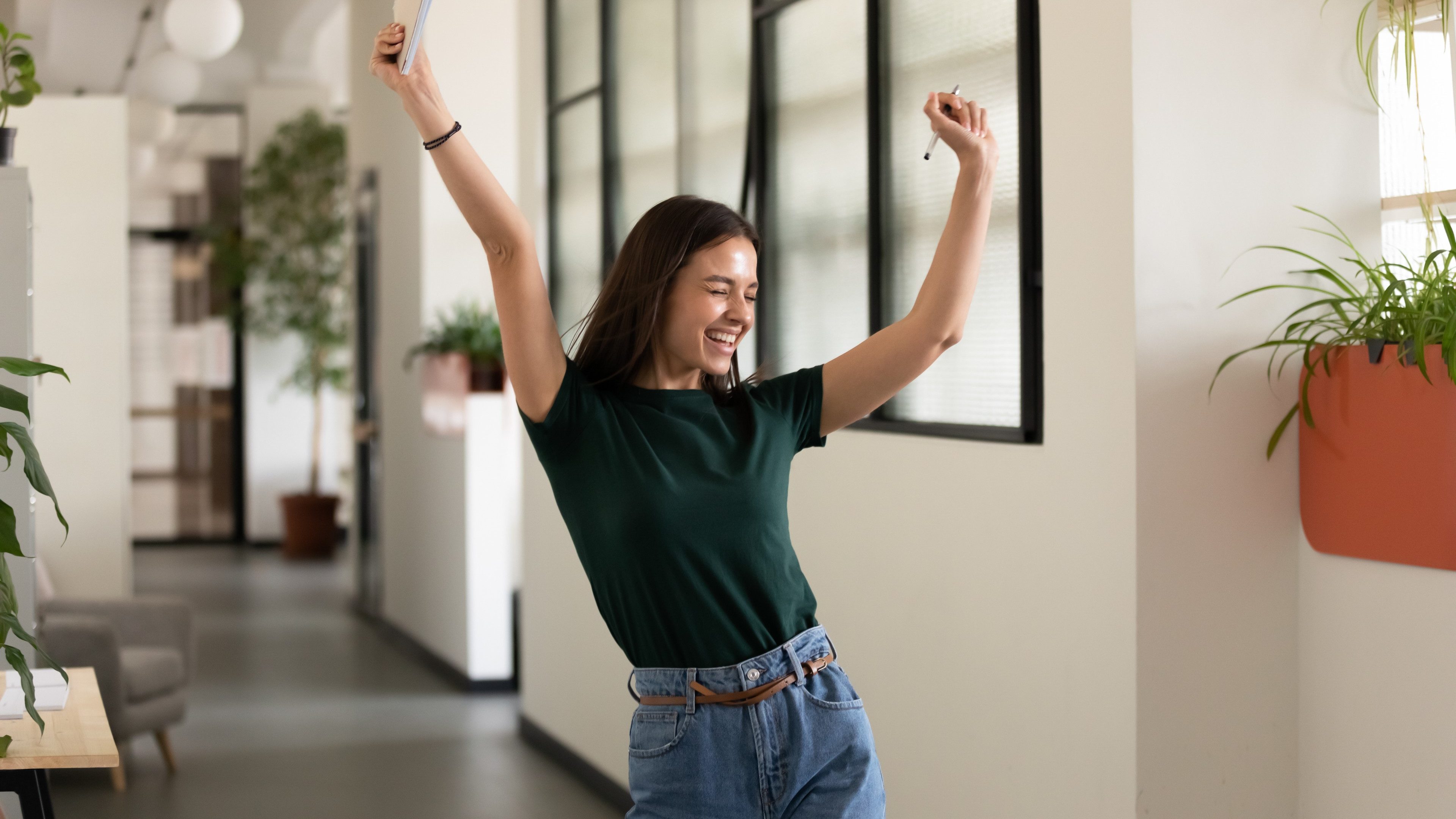 Emotional student girl within walls of institute celebrating successful exam pass, high school or college admission, european employee raised hands feels happy by salary growth, got promoted concept
